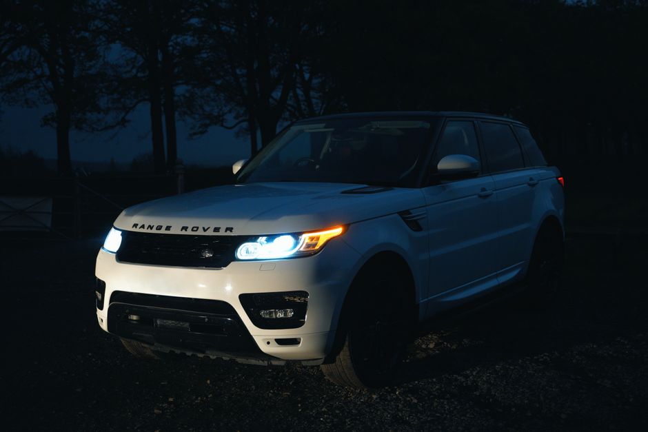 A white Range Rover SUV captured at night with its headlights illuminating the dark surroundings for a sleek look.